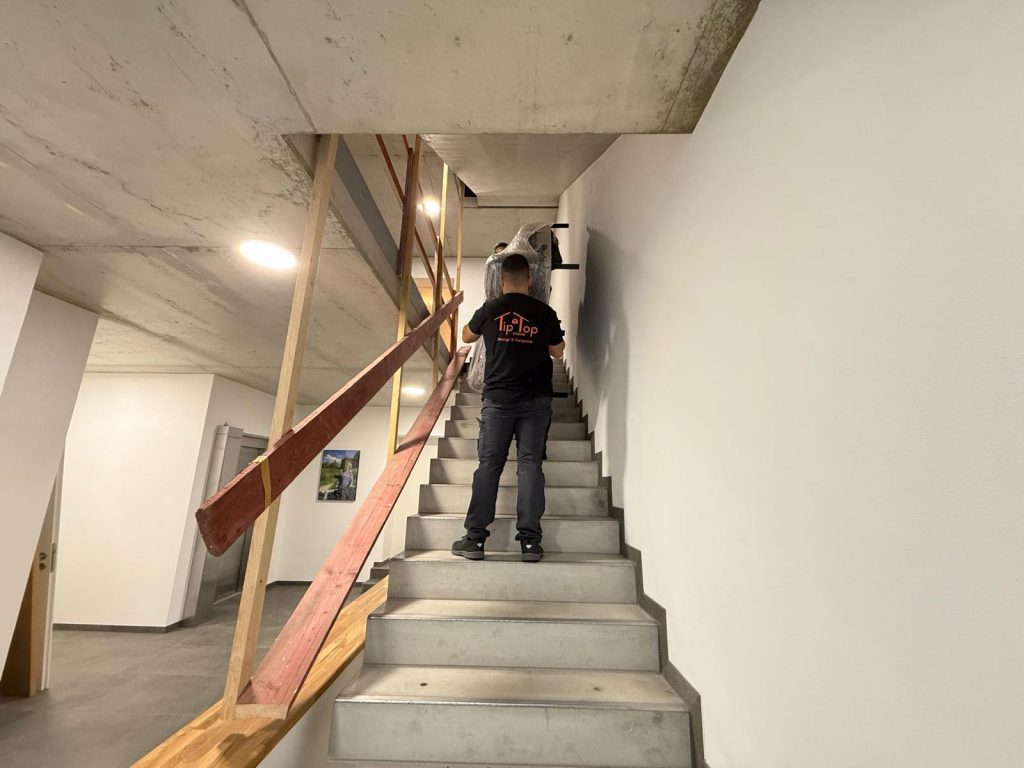 Mitarbeiter von TipTop Move trägt Umzugsgut über eine Treppe