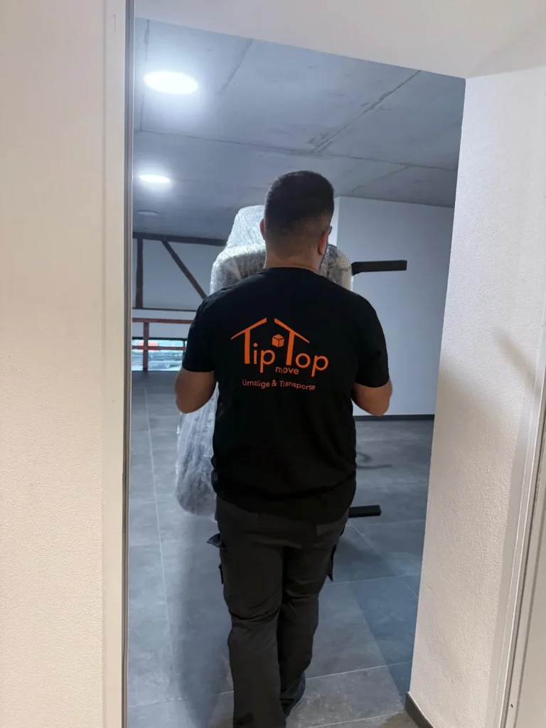 Mitarbeiter von TipTop Move trägt Umzugsgut beim Firmenumzug durch ein Bürogebäude in Konstanz