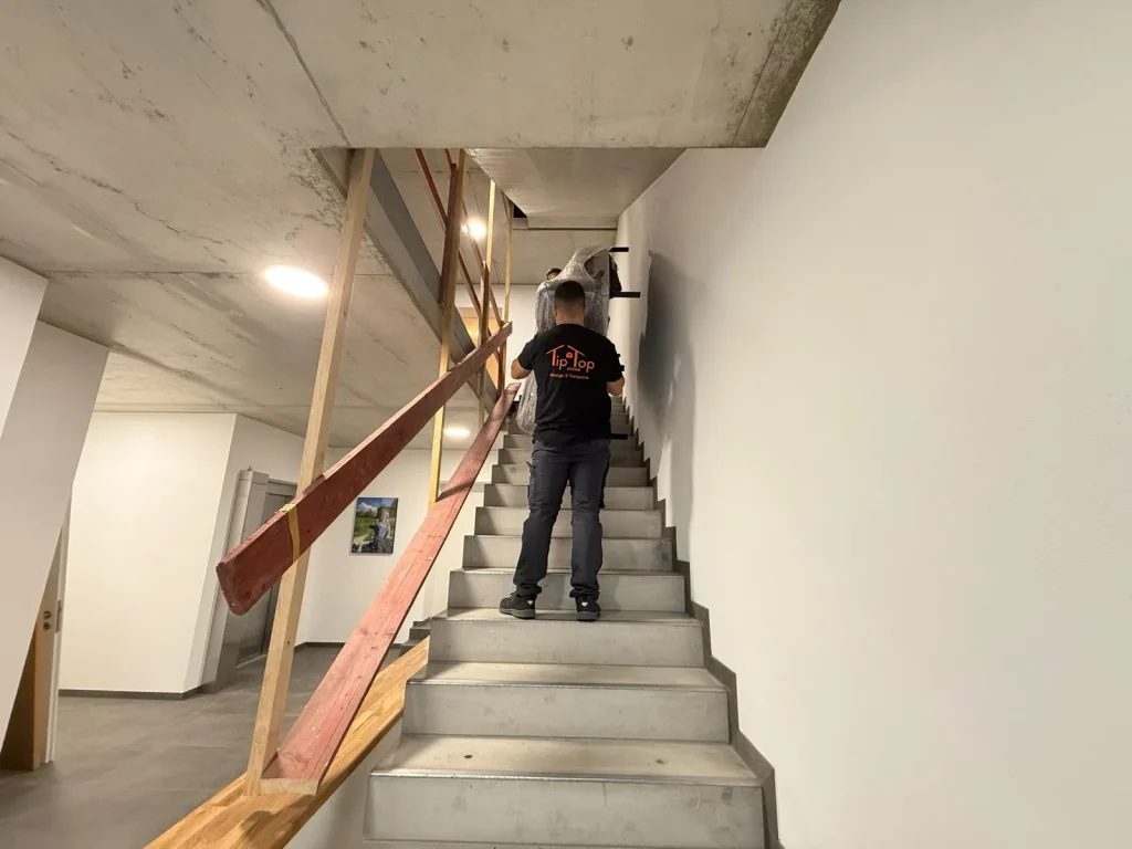Mitarbeiter von TipTop Move trägt Umzugsgut durch ein Treppenhaus