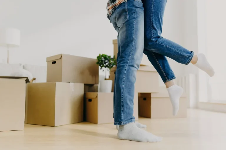 Junges Paar freut sich zwischen Umzugskartons in der neuen Wohnung