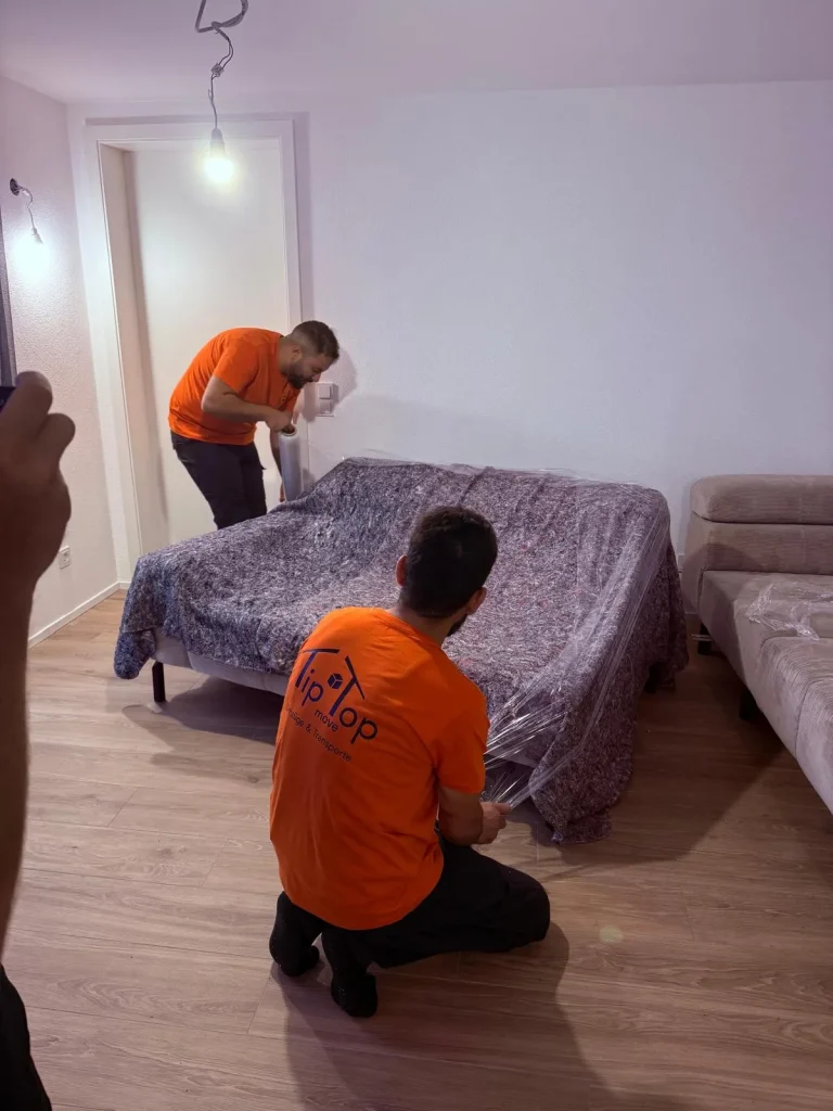 Umzugshelfer von TipTop Move verpacken Möbel mit Schutzdecken